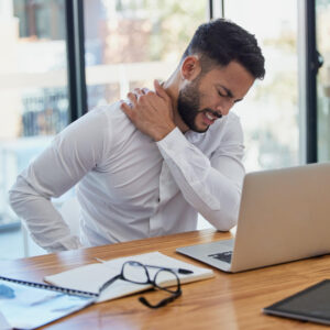 Hombre con dolor de espalda frente al portátil
