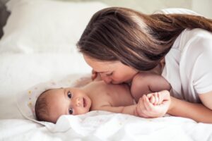 Madre acostada sonriendo junto a su bebé